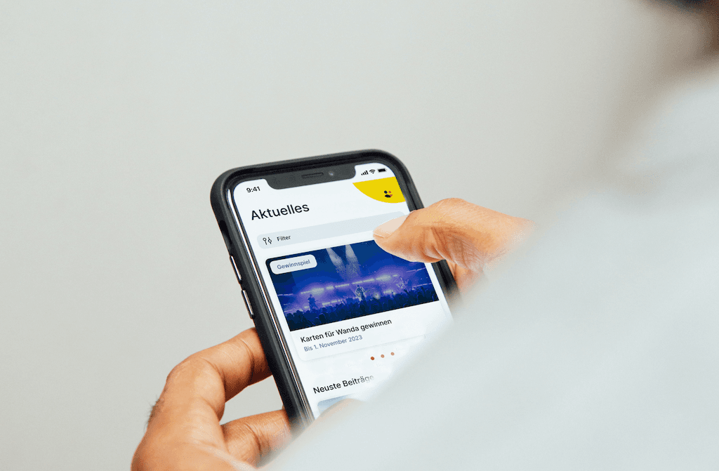 Hand hält ein Smartphone, dass die Kärntner Familiekarten App zeigt.